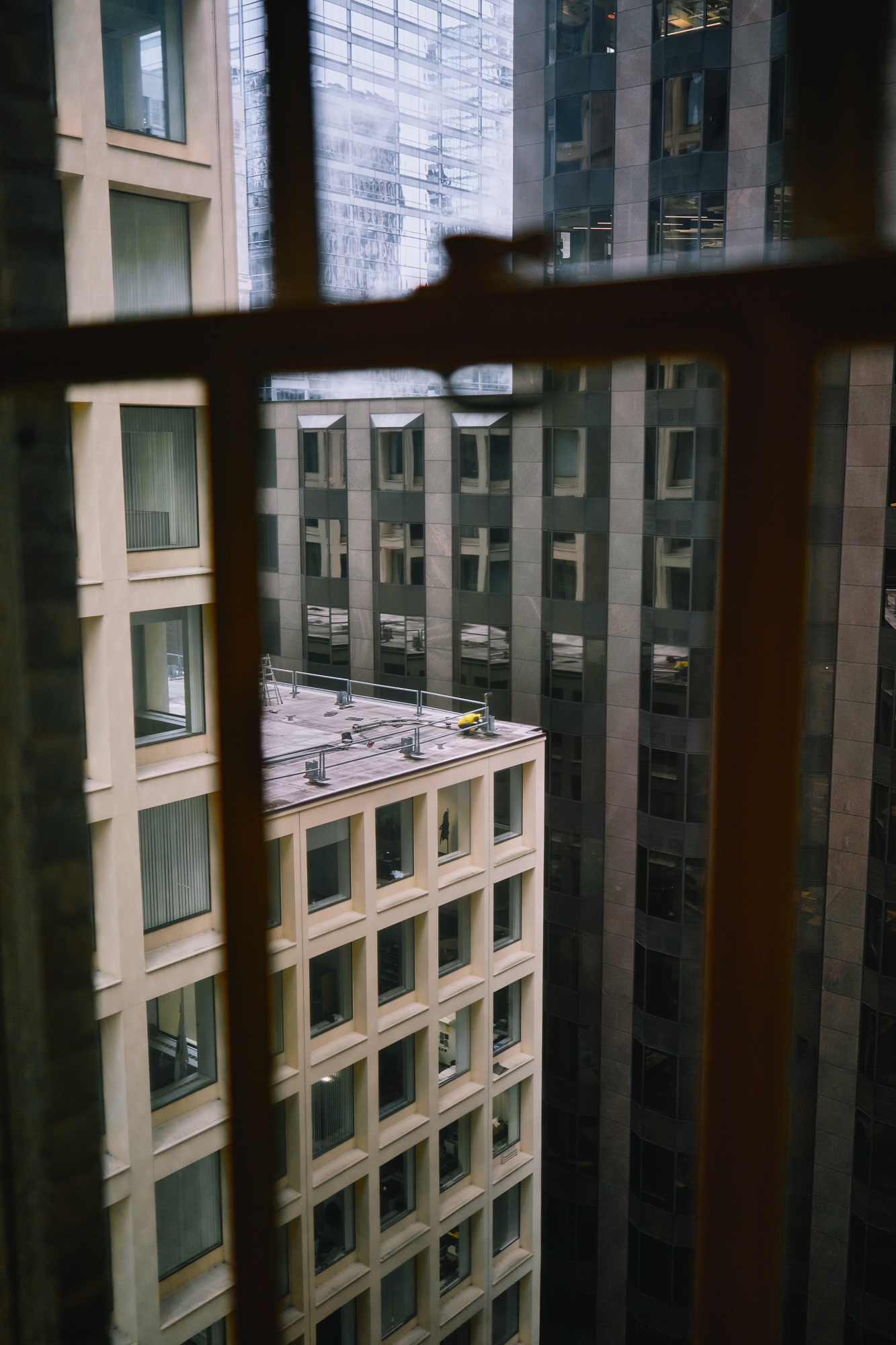 A man is seen doing maintenance work on the corner of a building in a city.