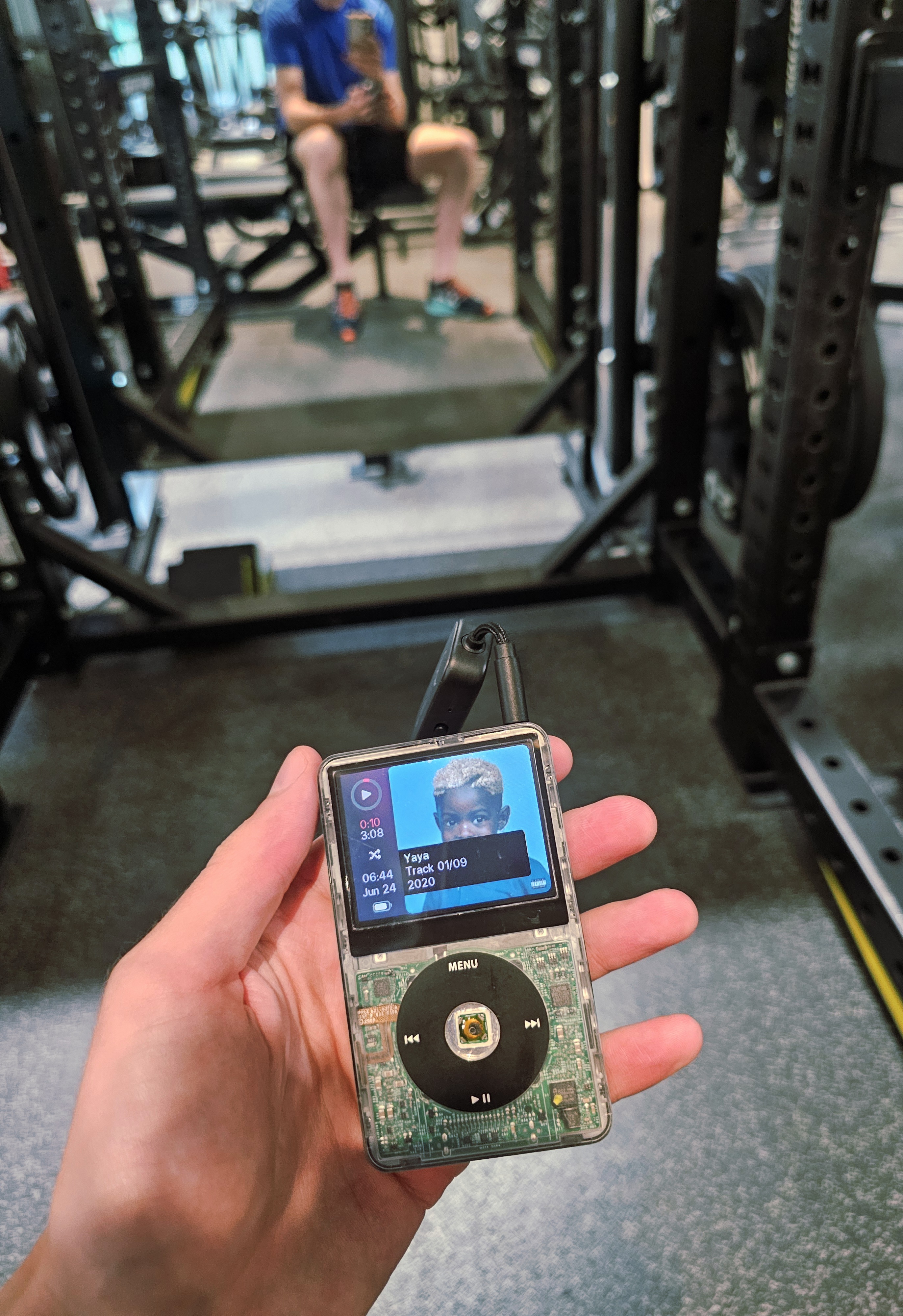 A hand holding an iPod in a gym.